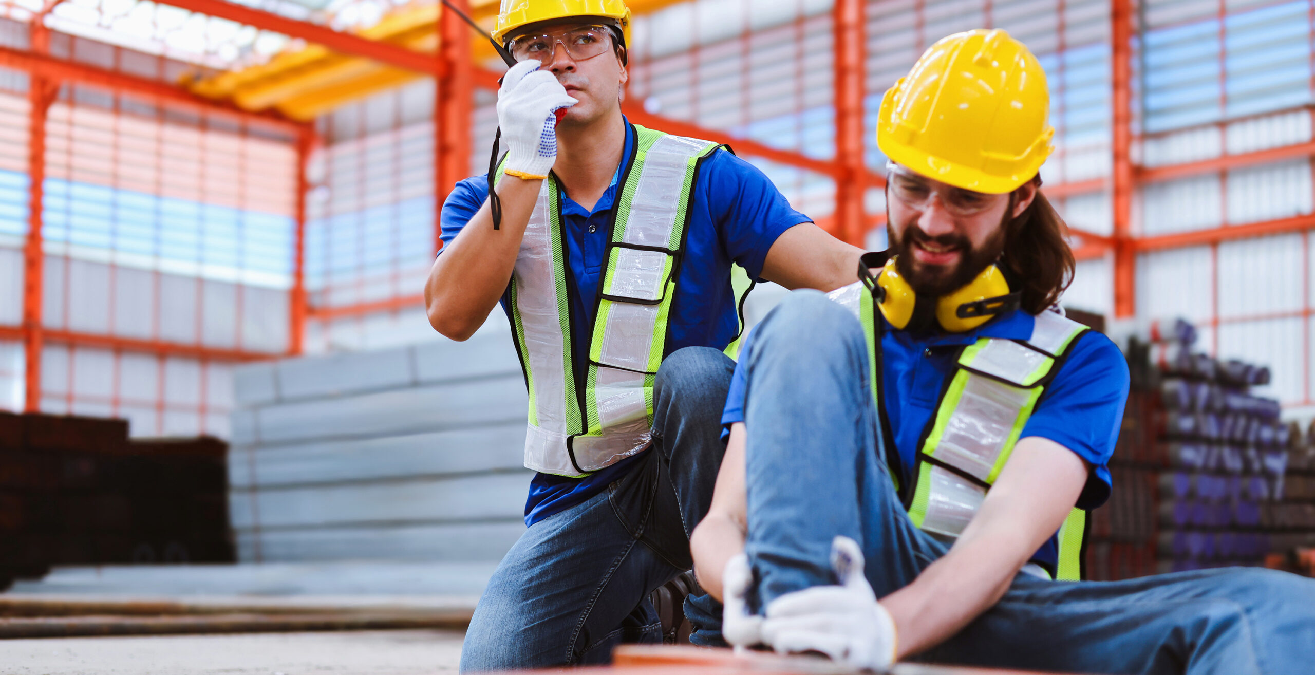 foreman using walkie-talkie to contact safety team for help while co-worker had a steel frame crush his leg at industrial factory.